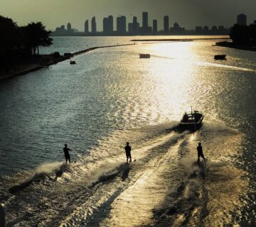 Silhouette people sea by city against sky sunset 360x320